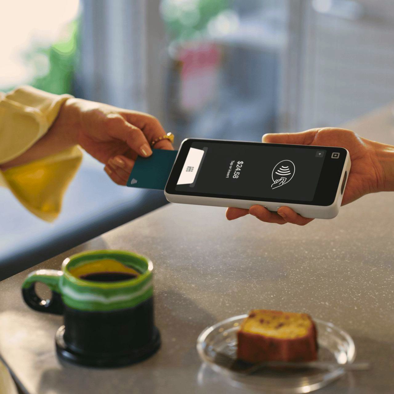 A customer tapping a card on a Square Handheld at a coffee bar