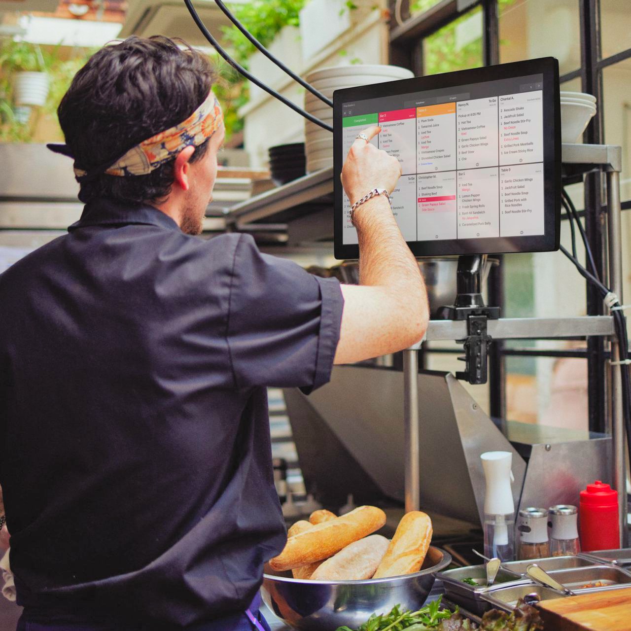 A line cook tapping a ticket on a Square kitchen display
