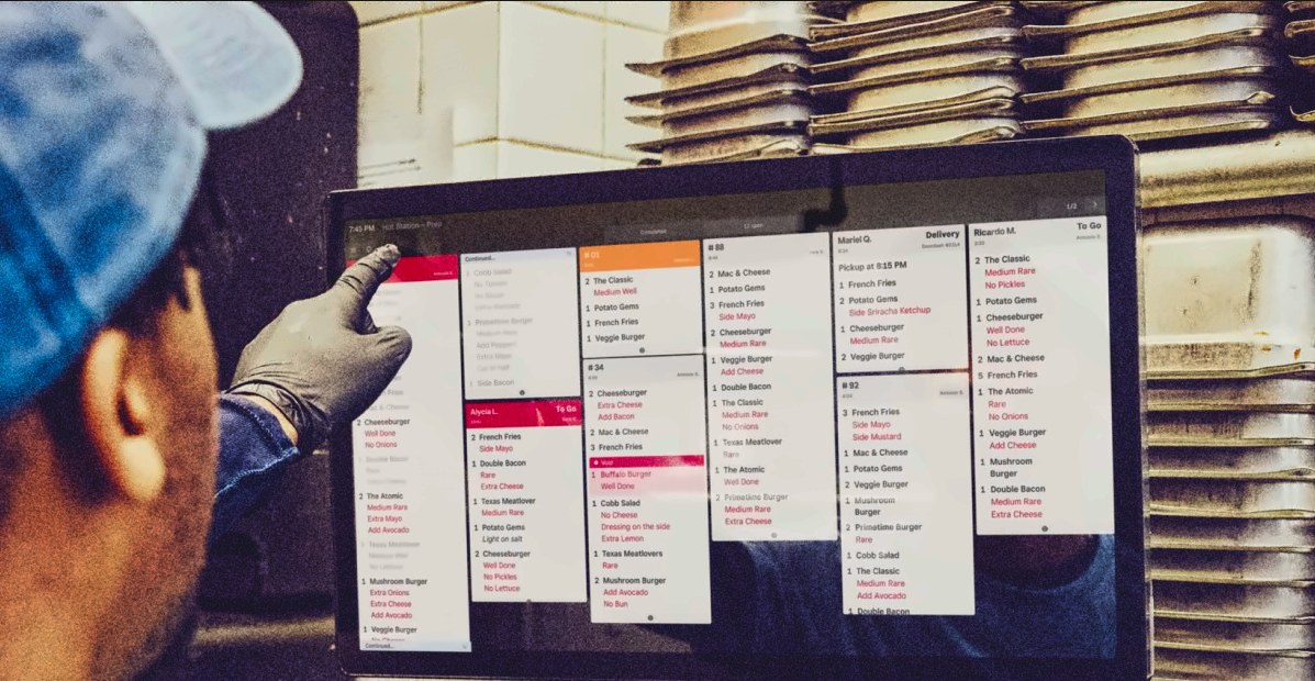 A cook pointing at open orders on a Square kitchen display