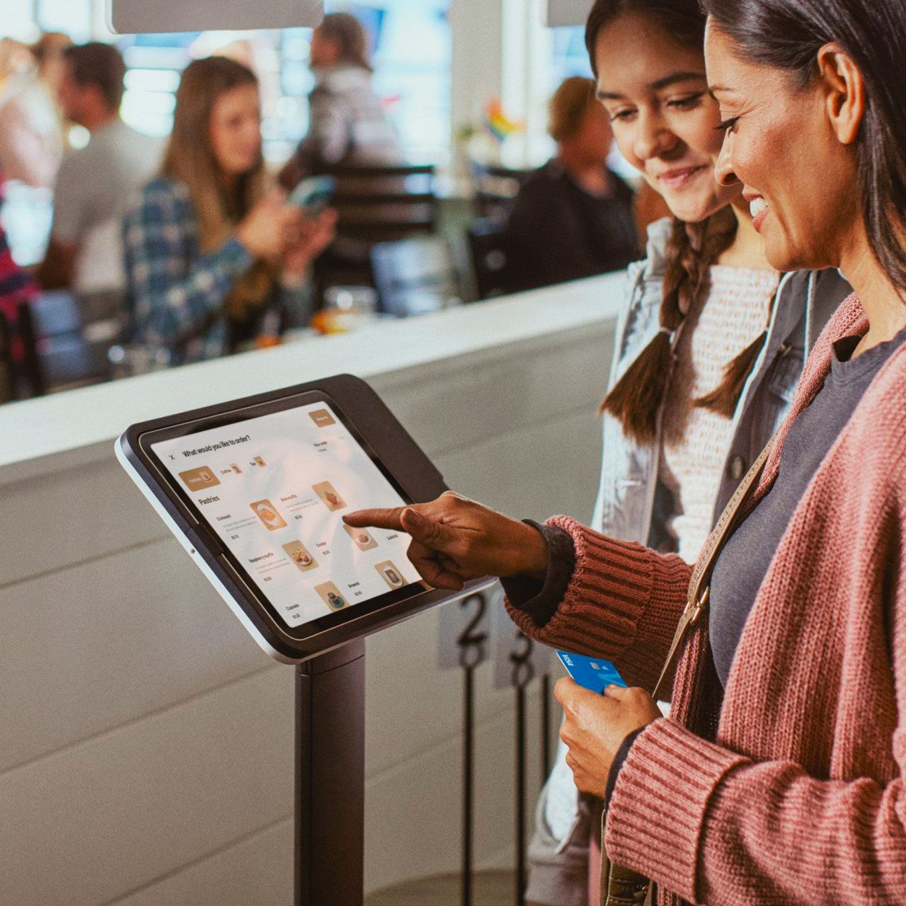 Two guests ordering on a Square Kiosk in a cafe