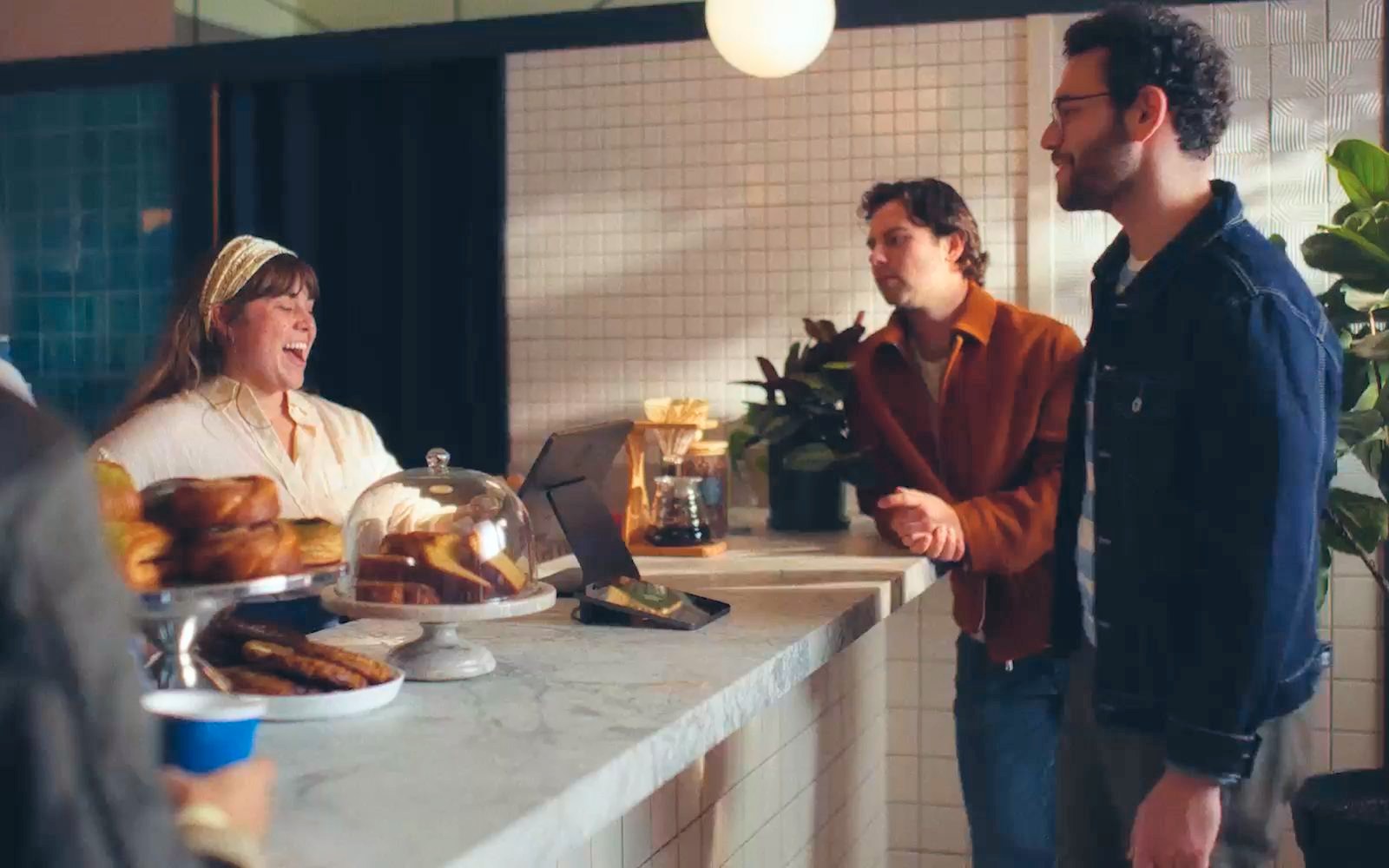 A Square Register installed on a cafe counter while staff serve customers