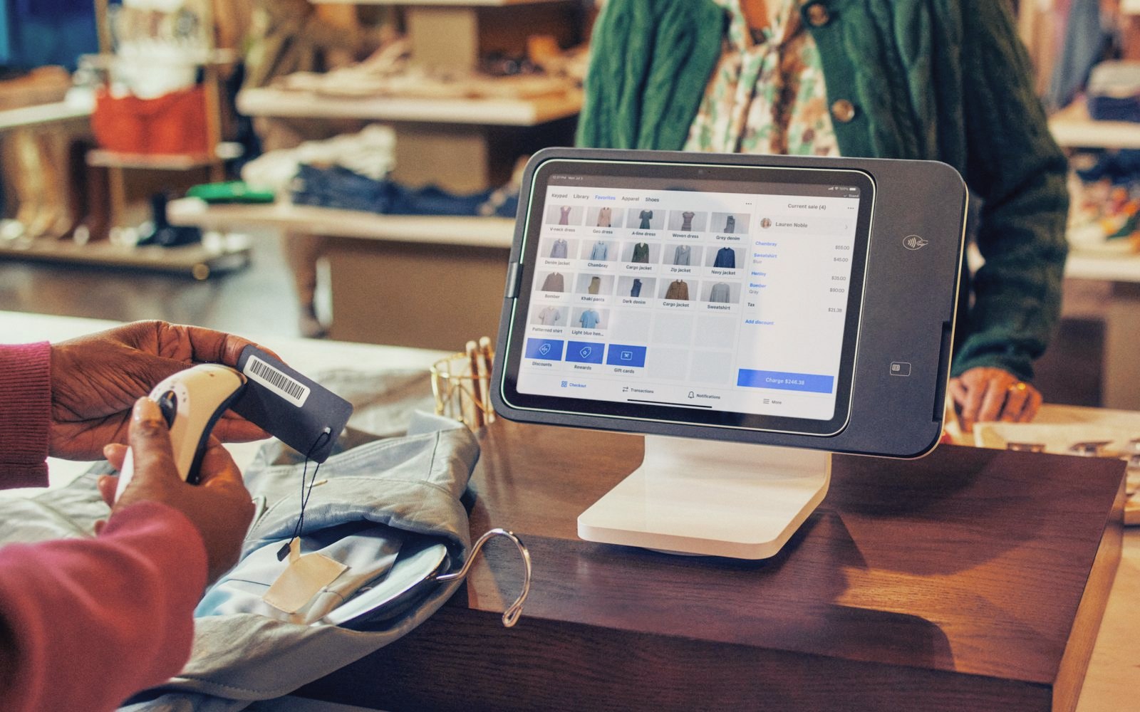 An associate scans a price tag beside a Square Stand (2nd generation) on a boutique counter
