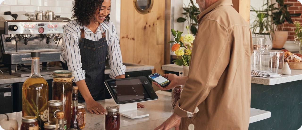 A customer pays by phone at a Square Stand on a cafe counter